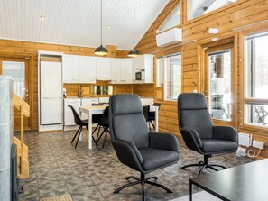 A modern kitchen with white cabinets, a dining area with a table and chairs, and large windows allowing natural light.