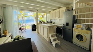 A modern kitchen with a view of the ocean, a dining area with a view, and a washing machine. - Blue Lagoon, Cottage feet in the water (Terre-de-Haut)