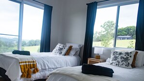 Ett hotellrum med två sängar, stora fönster och utsikt över omgivningarna.