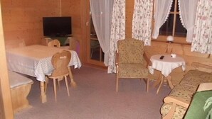 Une pièce en bois contenant un lit, une chaise, une table et un téléviseur.
