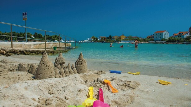 A beach with clear water, sand, and a few people in the distance. - Nice Home in Preko With Wifi and 2 Bedrooms (Preko)