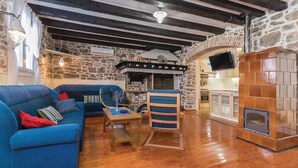 A cozy living room with a stone wall, a blue sofa, a wooden coffee table, and a fireplace. - Nice Home in Preko With Wifi and 2 Bedrooms (Preko)