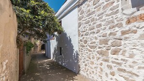 A narrow alleyway with a stone wall on one side and a white wall on the other. There is a staircase leading down to a lower level. - Nice Home in Preko With Wifi and 2 Bedrooms (Preko)