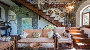 Ein gemütliches Interieur mit Steinwand, einer Holztreppe, einer gepolsterten Couch und einem Holztisch.