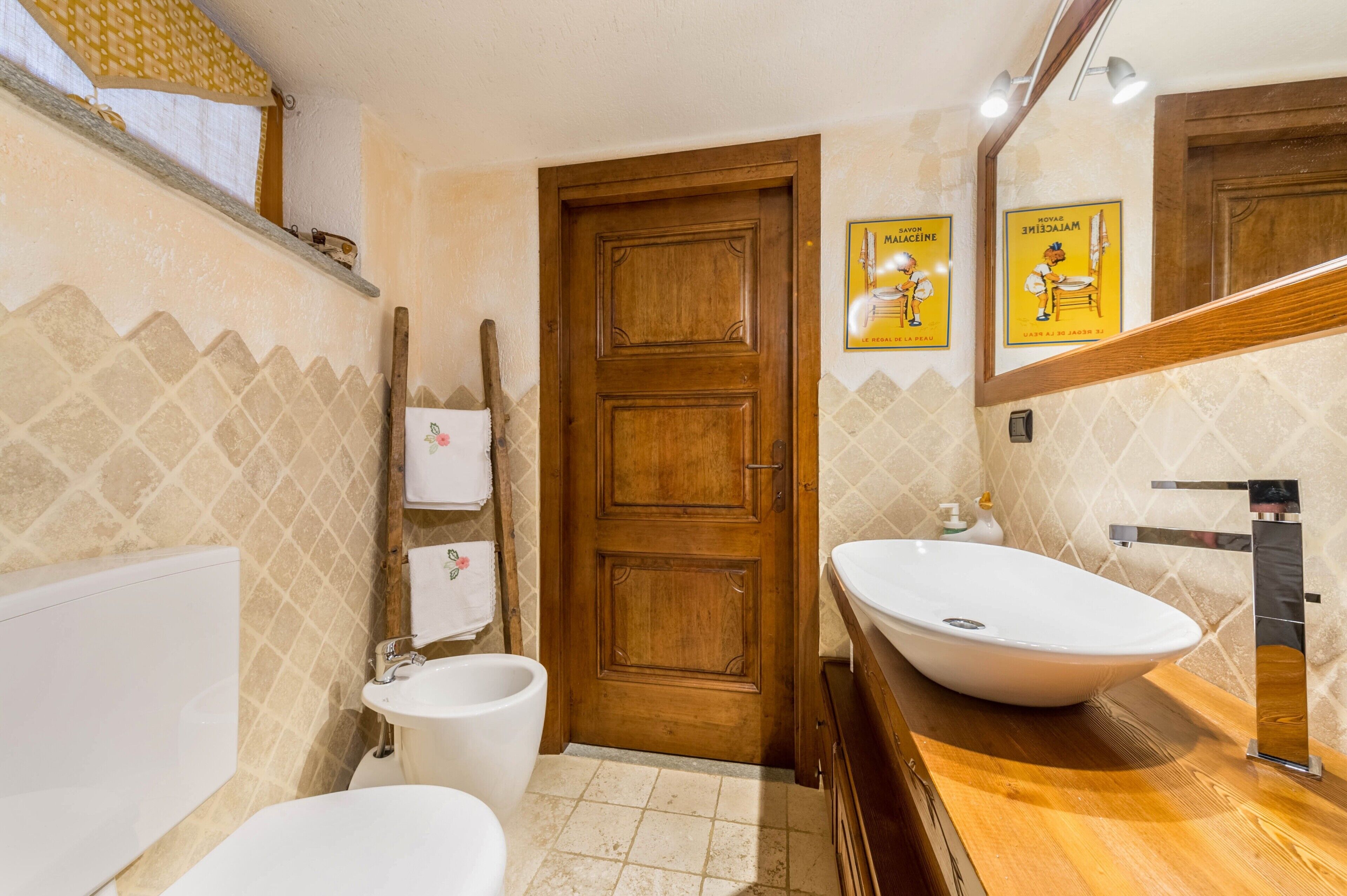 A bathroom with a wooden door, a white sink, a bathtub, and a toilet.