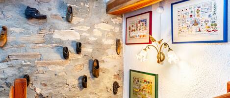 A stone wall with shoes, wooden beams, and framed pictures.