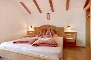 A bed with a wooden headboard, two bedside tables with lamps, and a framed picture on the wall.