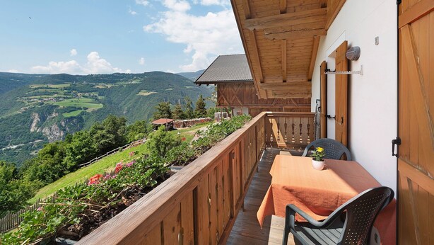A balcony with a table and chairs, overlooking a mountainous landscape. - Apartment "Stinerhof - Panoramablick" with Mountain View, Balcony & Garden (Völs am Schlern)