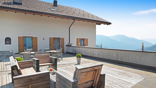 A terrace with wooden furniture, a potted plant, and a view of mountains. - Apartment "Stinerhof - Schlernblick" with Mountain View, Wi-Fi, Balcony & Garden (Völs am Schlern)