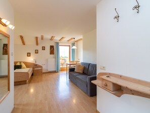 Amplia sala de estar con piso de madera, un sofá, una mesa de comedor y una barra de cocina.