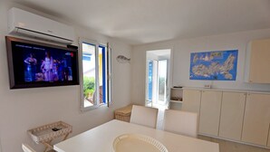 Een moderne keuken met witte kasten, een eettafel met een witte dienblad en een aan de muur bevestigde televisie.