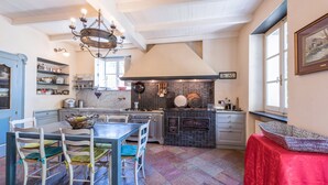 Een keuken met een eettafel, stoelen, een kroonluchter en een rode tafelkleed.