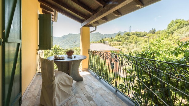 Een balkon met een tafel, stoelen en uitzicht op een bergachtig landschap.