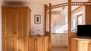 A wooden interior with cabinets, a television, and a kitchen area. - Apartment 'Kristiania Type A2' with Mountain View, Sauna, Balcony & Garden (Siusi allo Sciliar (BZ))