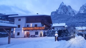 Ein verschneites Dorf mit Häusern, einem Holzzaun und einem Berg im Hintergrund.