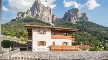 Ein zweistöckiges Gebäude mit einem Balkon, beschriftet mit 'Kristiania Residence', vor einer Bergkulisse.