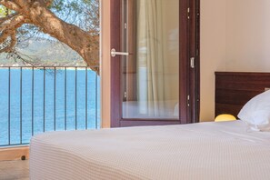 A bedroom with a bed, a door with a view to the sea, and a balcony with a railing. - Villa Lumb with Private Access to the Sea, Sea & Mountain View, Pool, A/C, Wi-Fi, Garden & Terrace (capdepera)