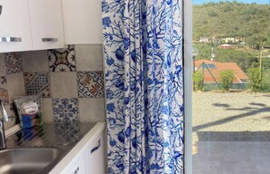 Une cuisine avec des carreaux décoratifs, un évier et une vue sur une colline parsemée de maisons.