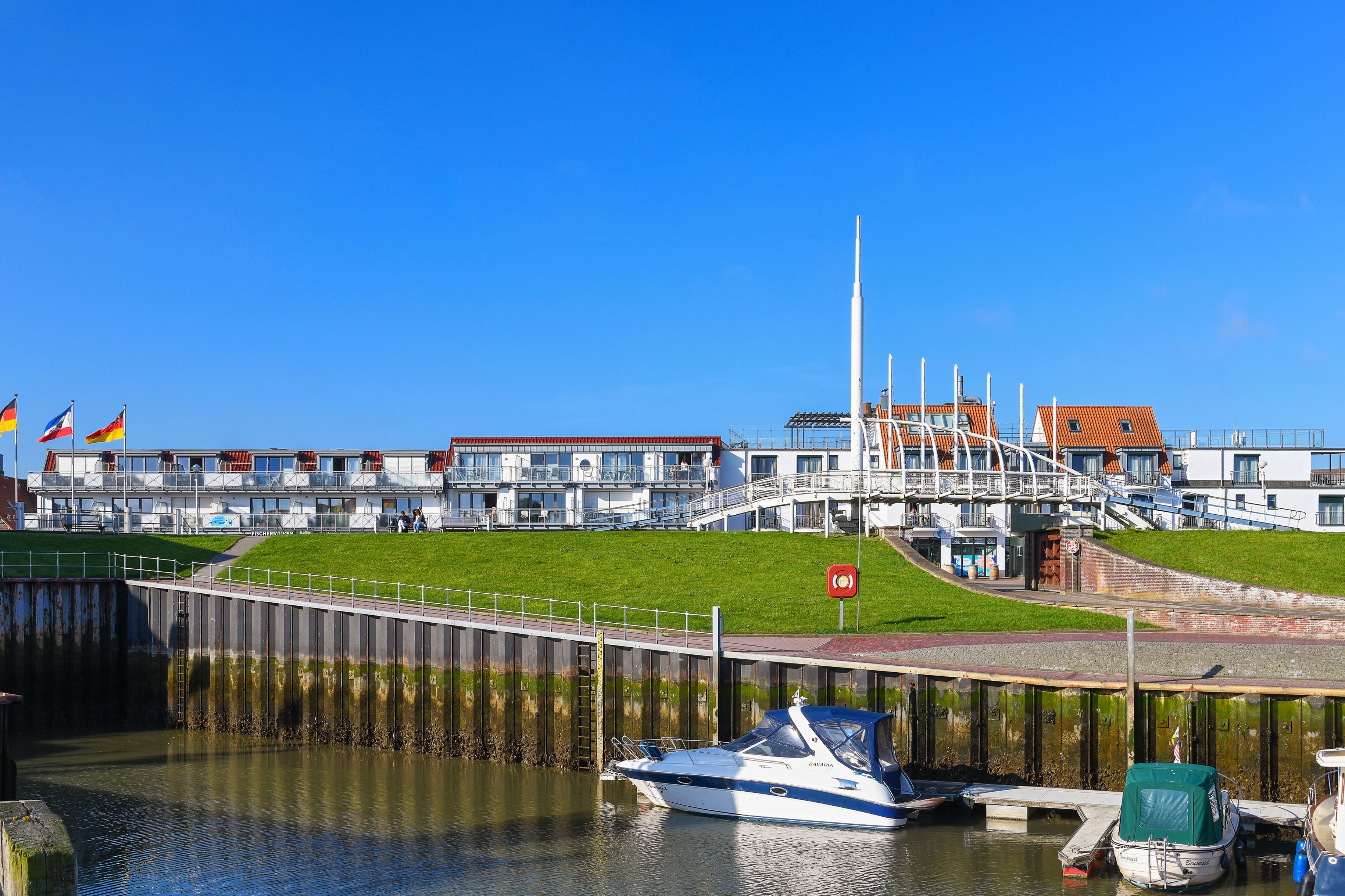 Une propriété située au bord de l’eau, dotée d’un port de plaisance, d’une berge verdoyante et d’un bâtiment avec de nombreux balcons.