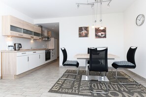 A modern kitchen with wooden cabinets, a coffee maker, and a dining area with a table and chairs.