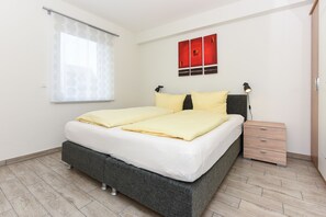 A bedroom with a bed, bedside tables, and a wall-mounted artwork.