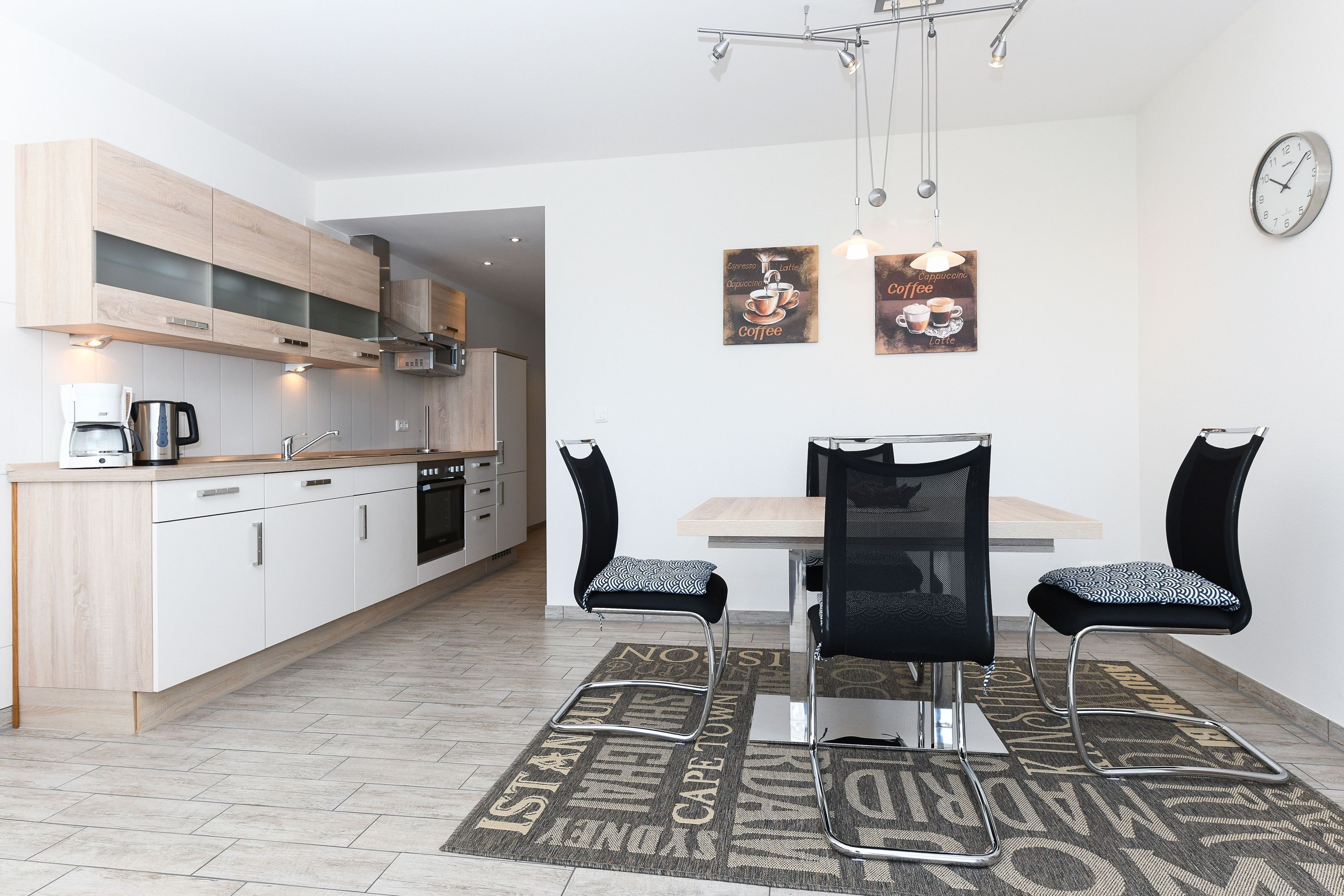 Eine moderne Küche mit Holzausstattung, einer Kaffeemaschine und einem Essbereich mit Tisch und Stühlen.