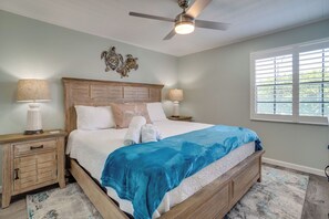 A bedroom with a bed, two bedside tables, a ceiling fan, and a window with blinds.