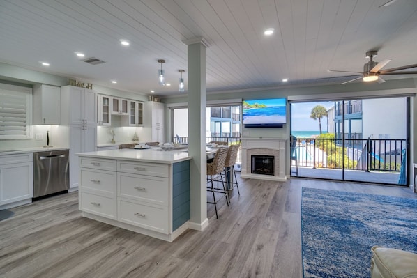 A modern kitchen with a large island, a dining area with a view, and a fireplace.