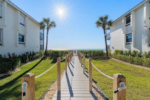 A pathway leading to a beachfront property with a clear view of the ocean.
