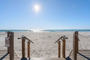 A wooden deck leading to a beach with a sign indicating no deck furniture allowed on the beach.