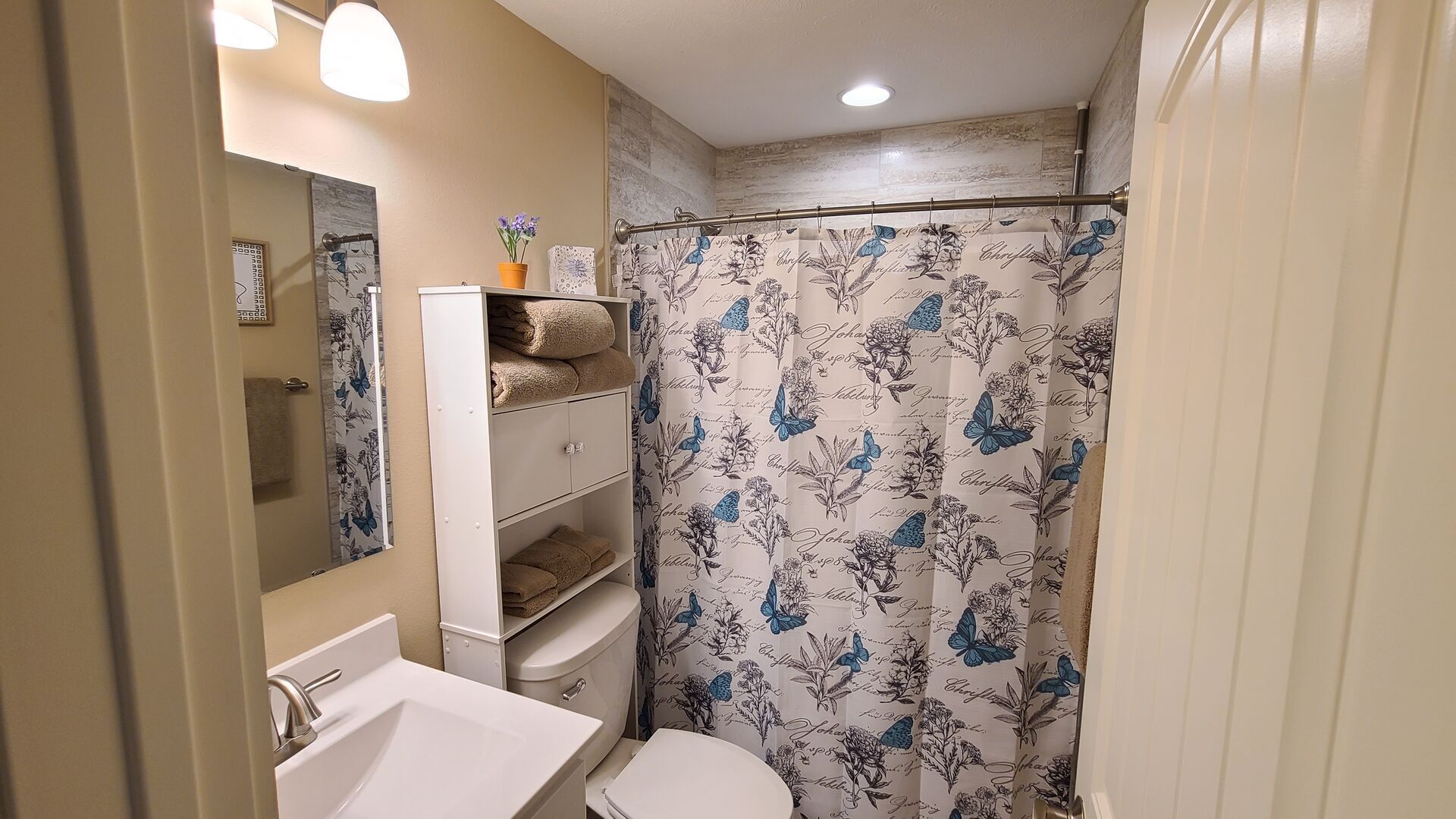 Een badkamer met een wit wastafel, toilet en douchegordijn met bloemenprint.