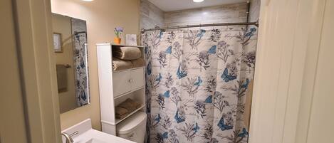 Een badkamer met een wit wastafel, toilet en douchegordijn met bloemenprint.