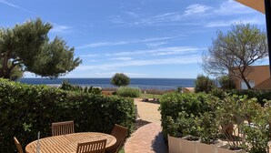 En terrasse med et bord og stole, havudsigt og forskellige planter.