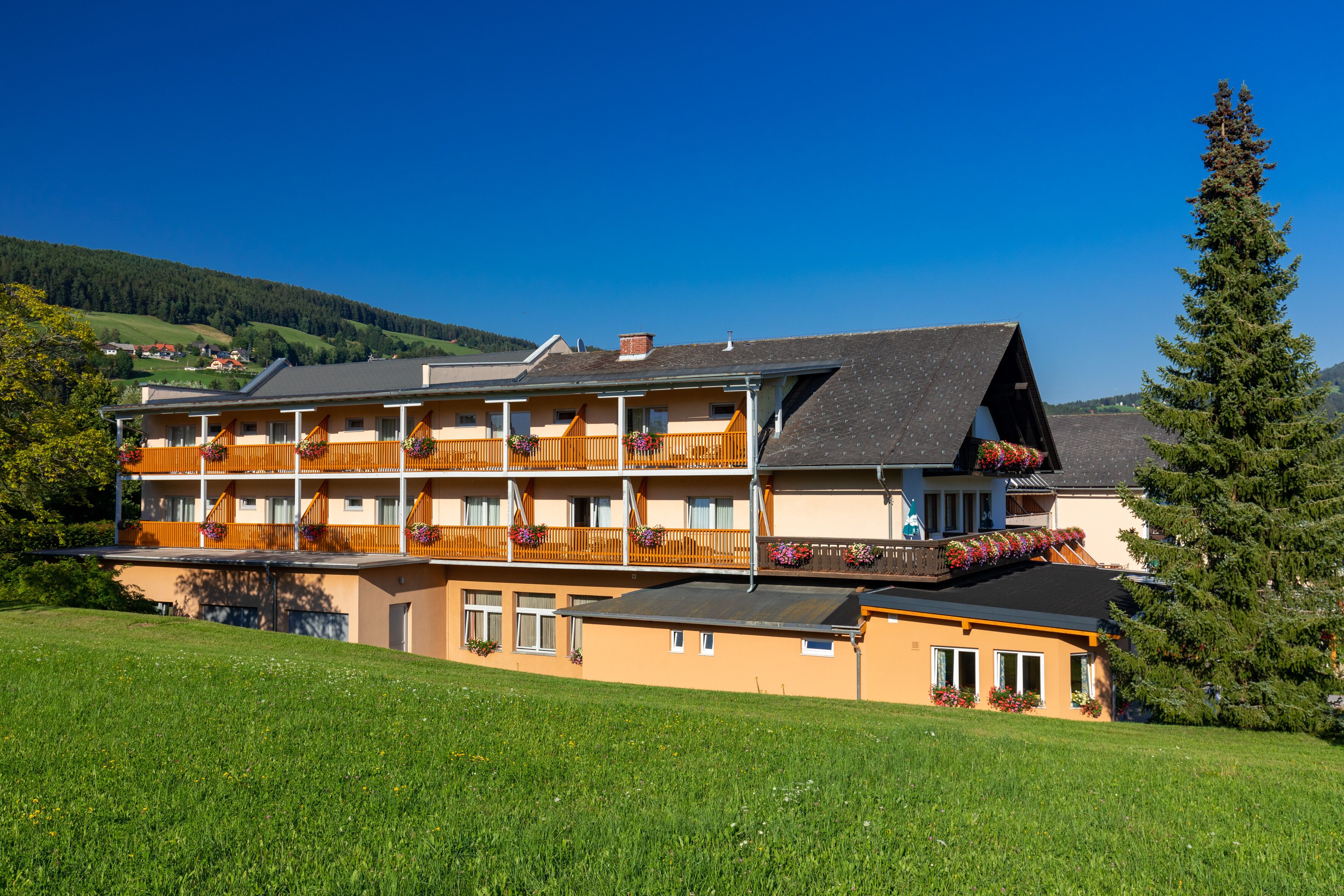 A multi-story hotel with balconies, flower boxes, and a view of the surrounding landscape.