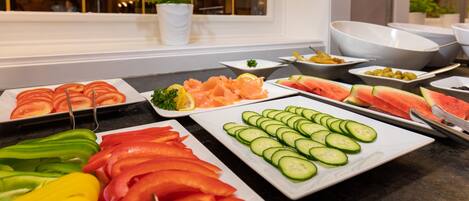 Un buffet proposant une variété de légumes et de fruits coupés en tranches.