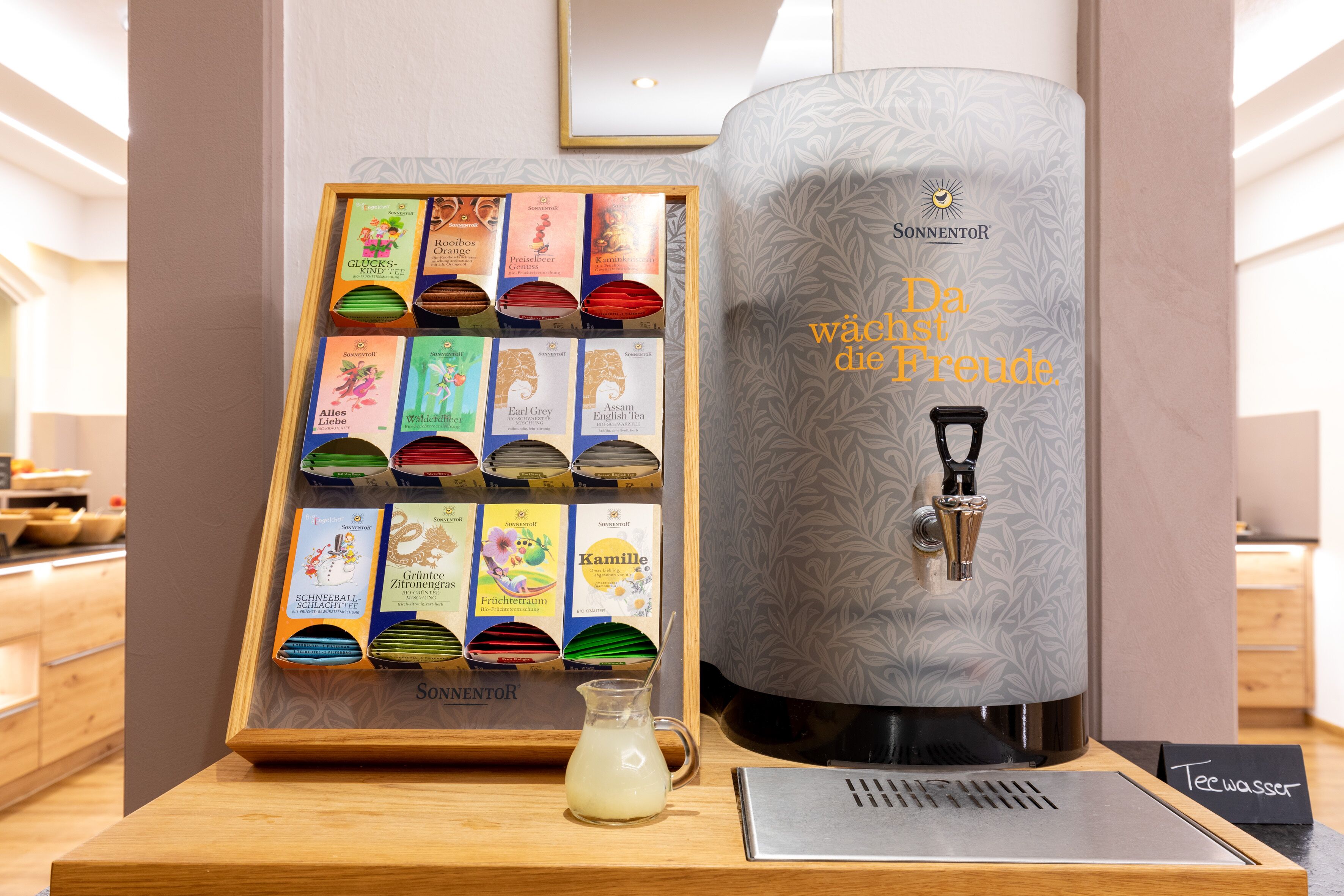 A coffee machine with a water dispenser and a display of tea boxes.