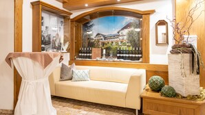 A cozy room with a large window, a wooden ceiling, a beige sofa, and a small table with decorative items.