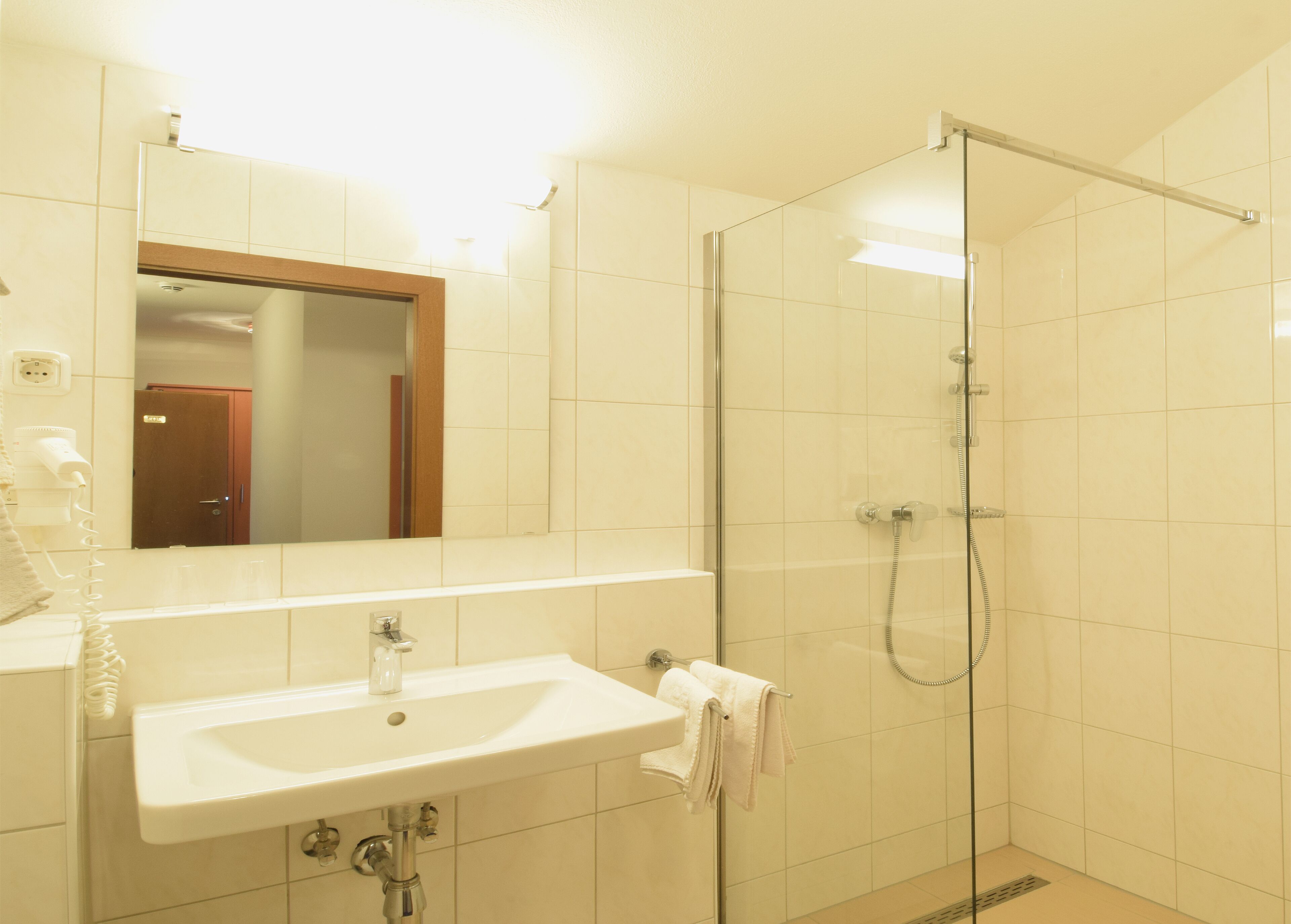 A bathroom with a white sink, a mirror, and a glass-enclosed shower.