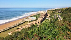 Un hôtel situé sur la côte, composé de plusieurs bâtiments, avec une plage et une vue sur l’océan.