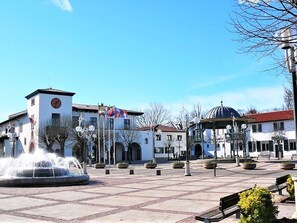 A public square with a fountain, benches, and a building with a clock tower.