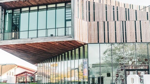 Un bâtiment moderne doté d’une façade à lattes de bois et de grandes fenêtres en verre.