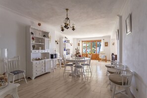A spacious dining area with a round table and white chairs, a white cabinet with decorative items, and a chandelier. - House on the beachfront with 4 bedrooms, 2 bathrooms and barbecue (Alcúdia)