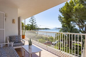 A balcony with a white railing, a white table, and a blue patterned sofa. - House on the beachfront with 4 bedrooms, 2 bathrooms and barbecue (Alcúdia)