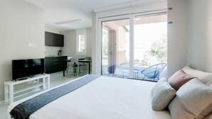 A modern hotel room with a large bed, a flat-screen TV, a desk, and a balcony with a chair. - Calm Studio near the center (WHITE STUDIO 8) (Locarno)