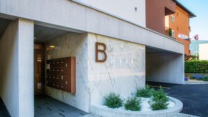 A building entrance with a marble facade, a large 'B' sign, and a small garden area. - Calm Studio near the center (WHITE STUDIO 8) (Locarno)