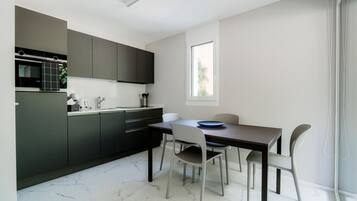 Une cuisine moderne avec des meubles de couleur sombre, un four encastré et une fenêtre qui laisse entrer la lumière naturelle.