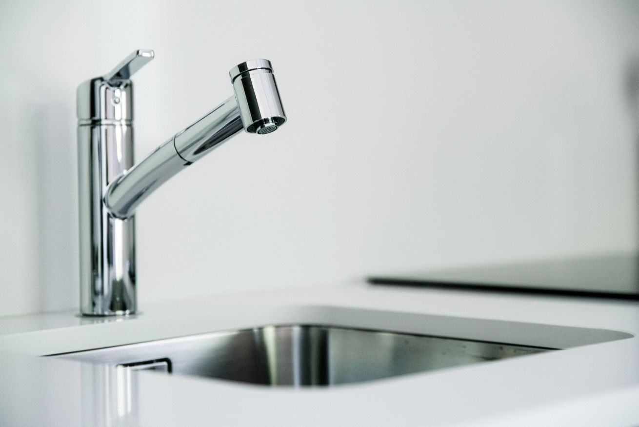 A modern kitchen with a stainless steel sink and faucet.