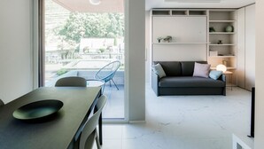 A modern living room with a sofa, a dining table with chairs, and a built-in shelving unit. - Calm Studio near the center (WHITE STUDIO 8) (Locarno)