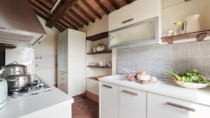 A kitchen with white cabinets, a stove, and a tiled backsplash. - Elks Tower (Toscana)