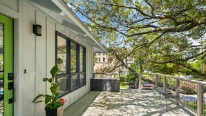 Une terrasse en bois agrémentée d’un pot de fleurs, d’un banc et offrant une vue sur la rue.